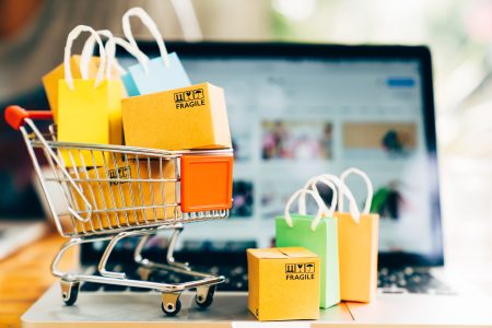 Product package boxes and shopping bag in cart with laptop computer which web store shop on screen for online shopping and delivery concept