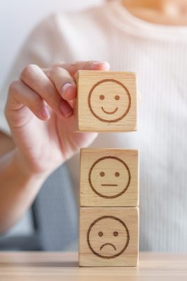 Hand choosing smile face from Emotion block for customer review, good experience, positive feedback, satisfaction, survey, evaluation, assessment, mood, world mental health day concept